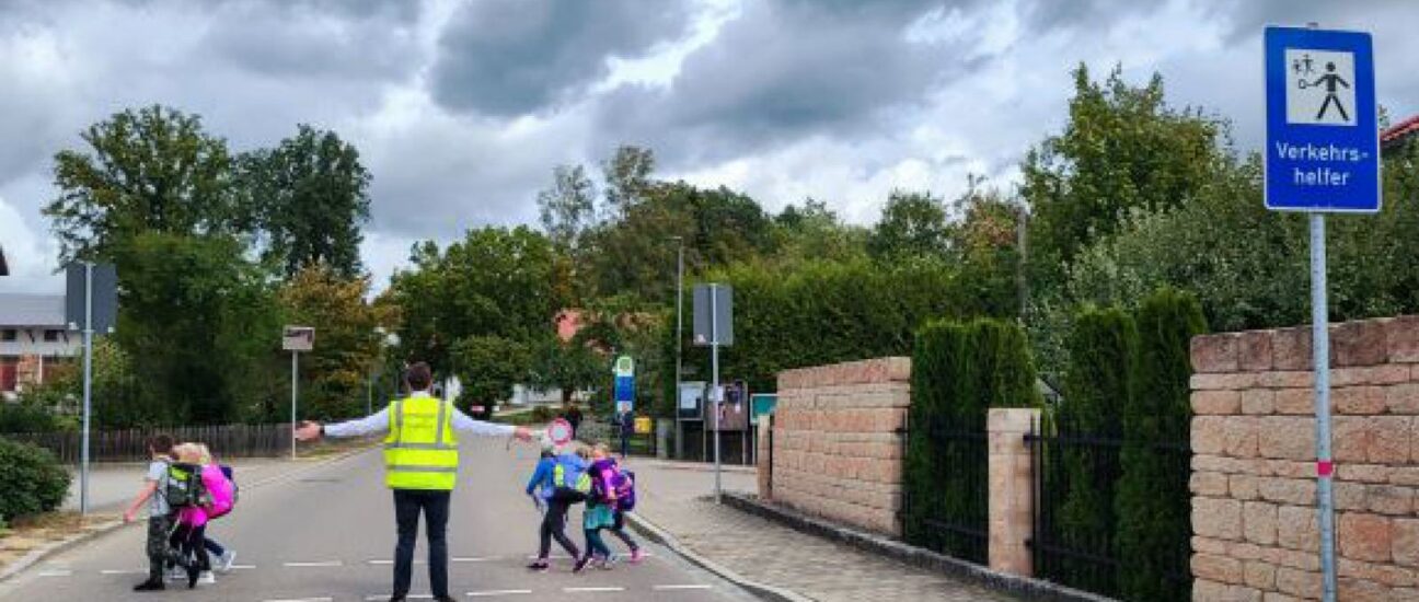 Schüler die mit Hilfe eines Schülerlotsen sicher die Straße überqueren